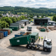 Ein Absetzkipper-LKW der AER GmbH bei der Bereitstellung von Containern auf einem Recyclinghof im Rhein-Lahn-Kreis vor einer ländlichen Kulisse.
